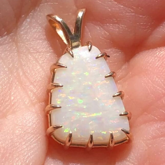 Opal pendant with gold setting on a hand